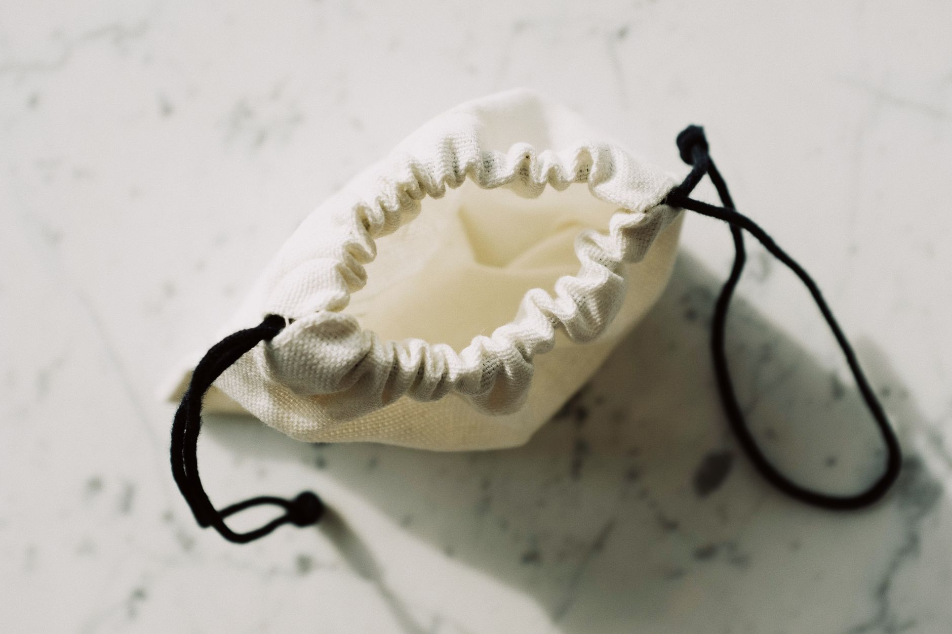 A soft leather pouch handbag with no handle resting on a neutral tabletop